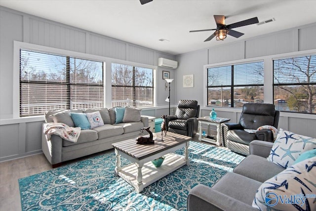 living room with a wall mounted air conditioner, ceiling fan, and hardwood / wood-style flooring