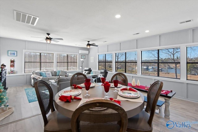 dining space with ceiling fan, light wood-type flooring, a textured ceiling, and an AC wall unit