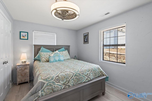 bedroom with ornamental molding and light wood-type flooring