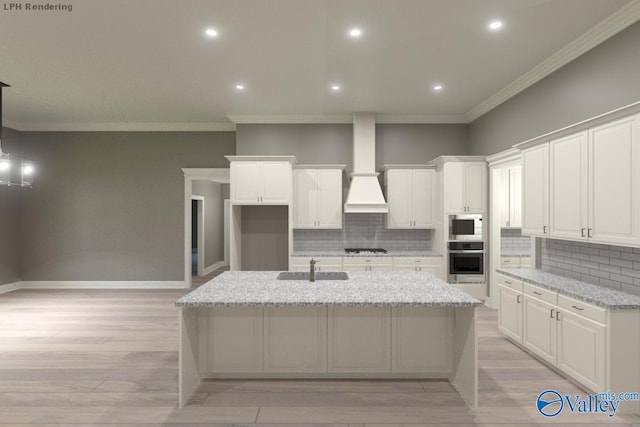 kitchen featuring stainless steel oven, wall chimney exhaust hood, white cabinets, gas cooktop, and a kitchen island with sink