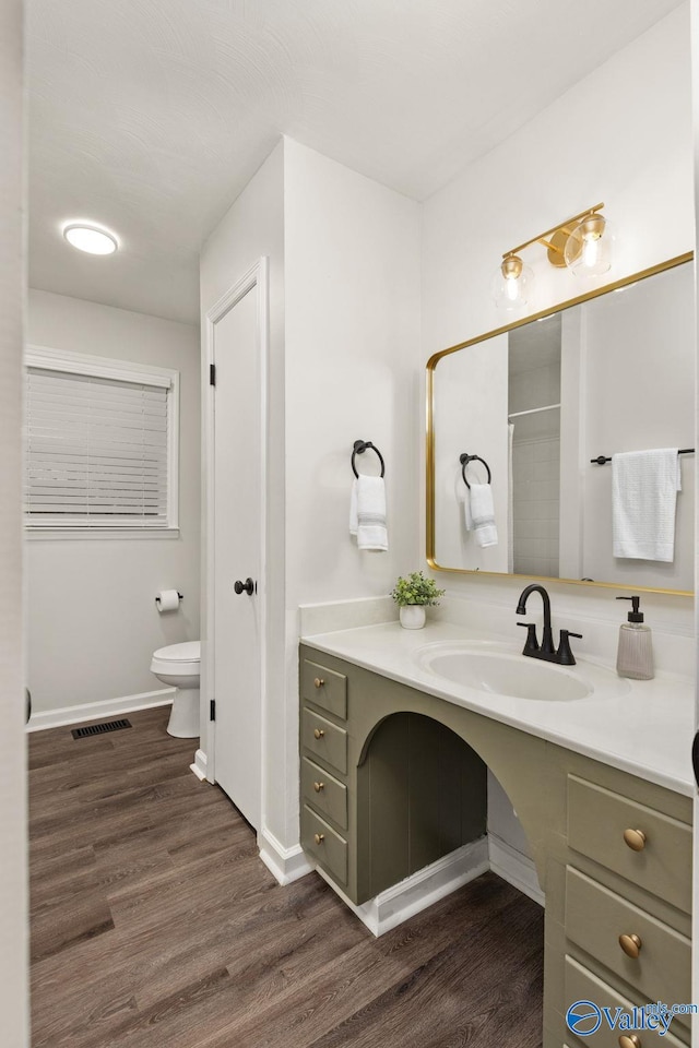 bathroom featuring hardwood / wood-style flooring, vanity, toilet, and a shower