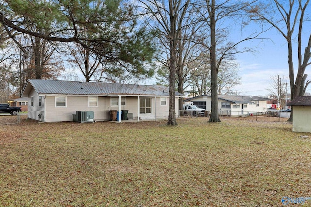 rear view of property featuring a lawn and central air condition unit