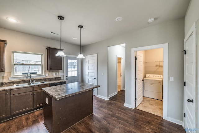 kitchen featuring sink, a center island, dark hardwood / wood-style flooring, washer / clothes dryer, and decorative light fixtures