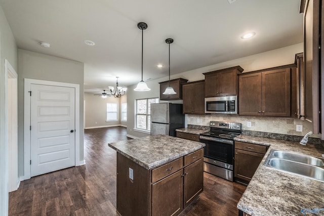 kitchen featuring appliances with stainless steel finishes, pendant lighting, tasteful backsplash, sink, and a center island