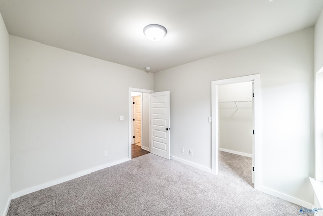 unfurnished bedroom featuring a closet, carpet flooring, and a spacious closet