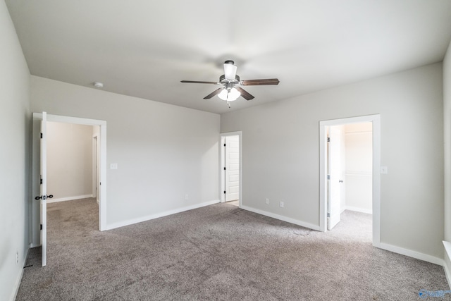 unfurnished bedroom with ceiling fan, a walk in closet, and light carpet