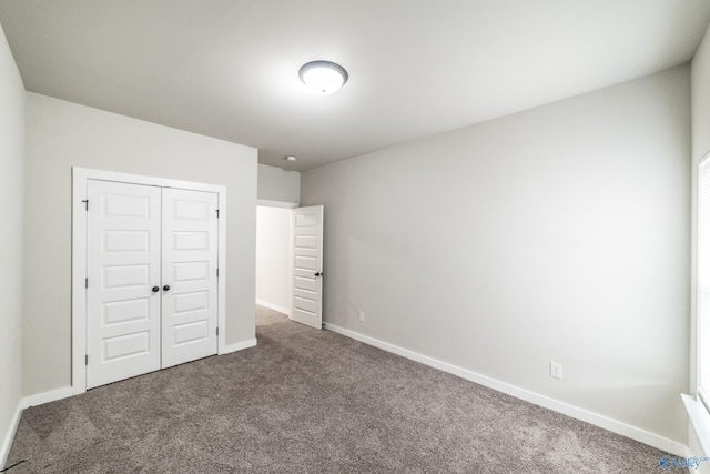 unfurnished bedroom featuring a closet and dark colored carpet