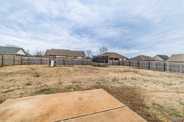 view of yard with a trampoline and a patio area