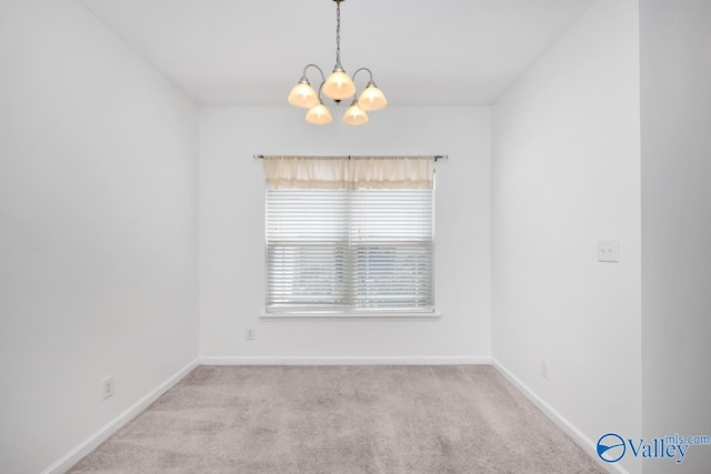 spare room featuring light colored carpet and a notable chandelier