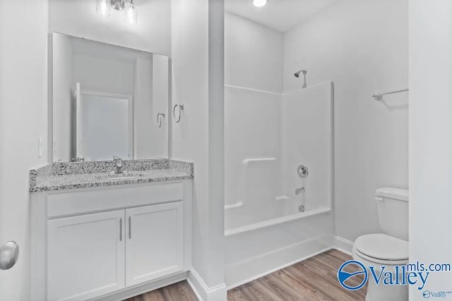 full bathroom featuring wood-type flooring, toilet, bathing tub / shower combination, and vanity