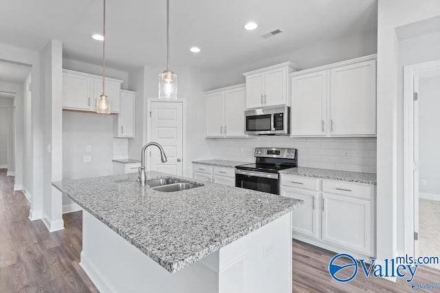 kitchen with an island with sink, appliances with stainless steel finishes, sink, and white cabinets