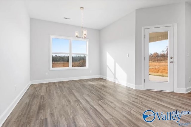 unfurnished dining area featuring hardwood / wood-style floors and a notable chandelier