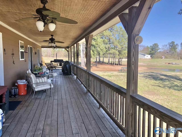 wooden terrace with covered porch and a yard