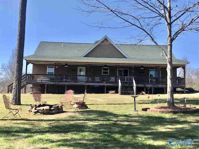 rear view of house with covered porch, a fire pit, and a lawn