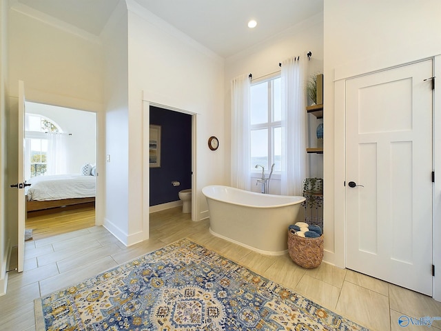 bathroom with toilet, hardwood / wood-style floors, a healthy amount of sunlight, and a washtub