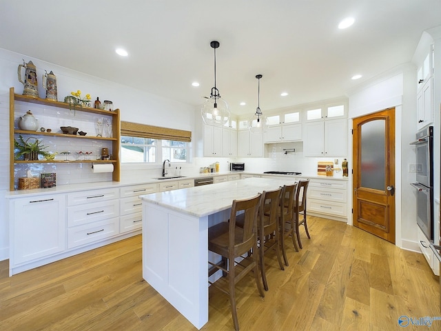 kitchen with a center island, light hardwood / wood-style floors, white cabinetry, and sink