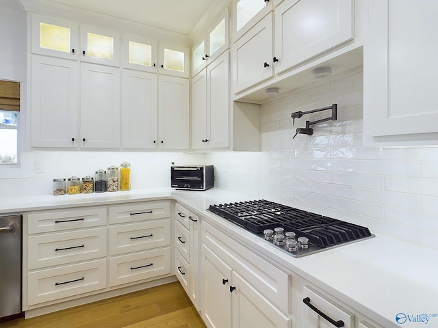 kitchen featuring backsplash, black gas cooktop, and white cabinetry