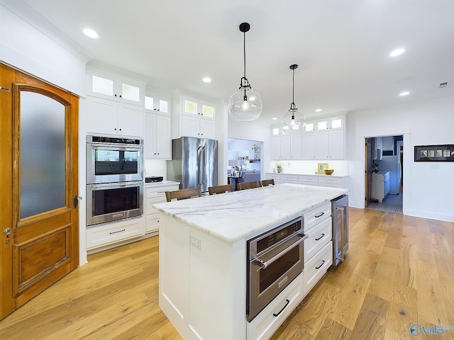 kitchen featuring white cabinetry, a center island, light hardwood / wood-style floors, and appliances with stainless steel finishes