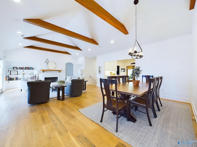 dining space with vaulted ceiling with beams, light hardwood / wood-style floors, and an inviting chandelier