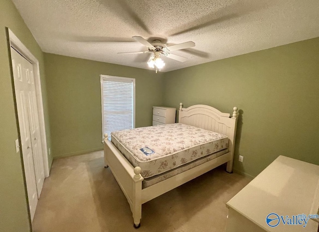 bedroom with light carpet, ceiling fan, a textured ceiling, and a closet