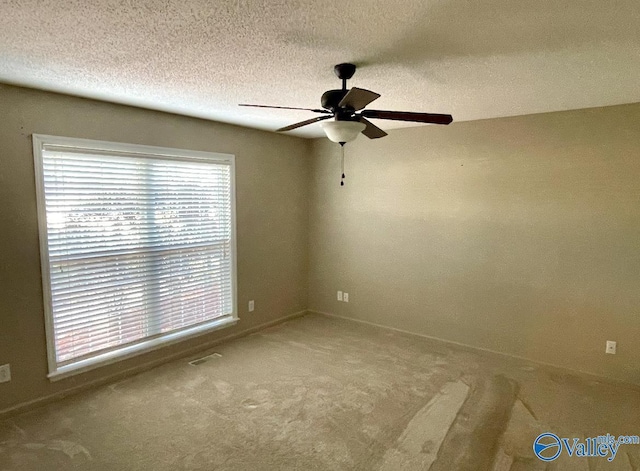 unfurnished room featuring a textured ceiling, visible vents, carpet flooring, and a ceiling fan