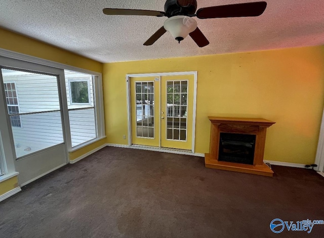 unfurnished living room featuring french doors, a fireplace with raised hearth, dark carpet, a textured ceiling, and baseboards