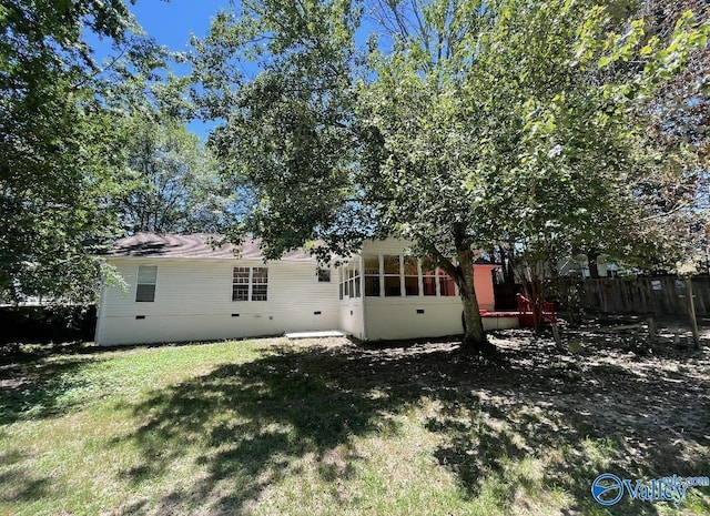 rear view of house featuring crawl space, fence, and a lawn