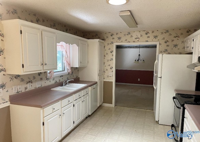 kitchen with light floors, white cabinetry, white dishwasher, a sink, and wallpapered walls