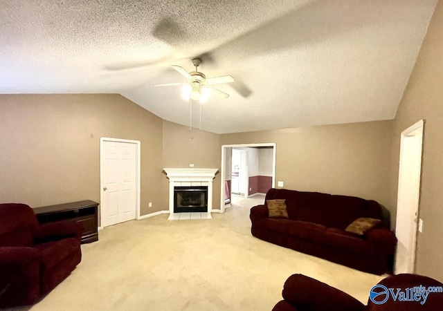 living room with lofted ceiling, ceiling fan, a fireplace with flush hearth, a textured ceiling, and carpet floors