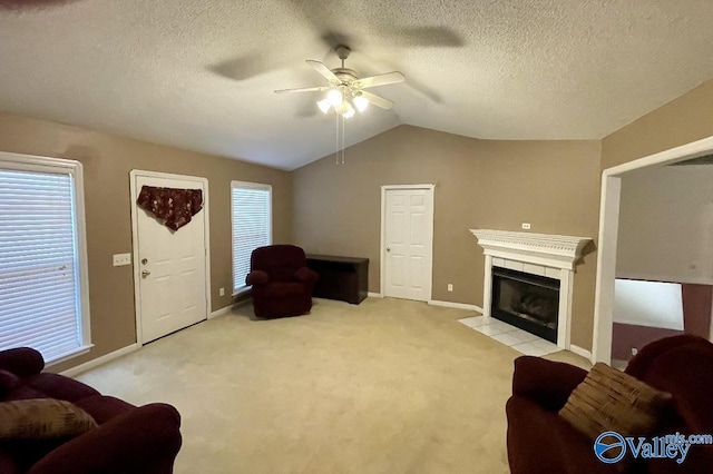 living room featuring lofted ceiling, a textured ceiling, a tile fireplace, light carpet, and a ceiling fan