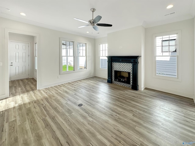 unfurnished living room with crown molding, a tiled fireplace, and light hardwood / wood-style flooring