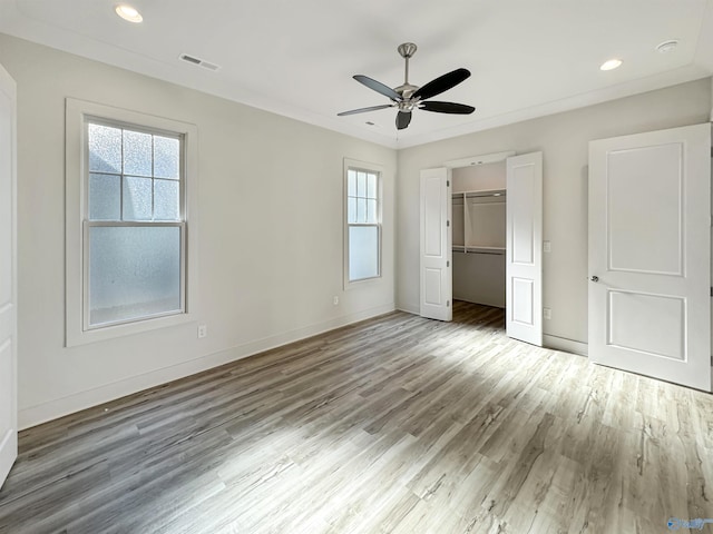 unfurnished bedroom featuring hardwood / wood-style flooring, crown molding, ceiling fan, and a closet