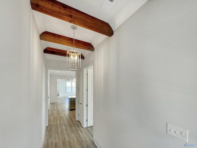 hallway with beamed ceiling, a notable chandelier, and light hardwood / wood-style floors