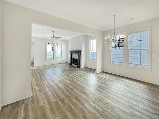 unfurnished living room featuring hardwood / wood-style flooring, crown molding, and ceiling fan with notable chandelier