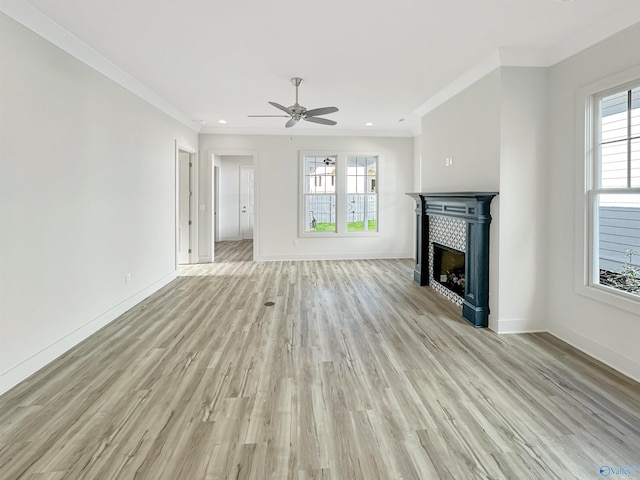 unfurnished living room with a tile fireplace, ceiling fan, crown molding, and light hardwood / wood-style flooring