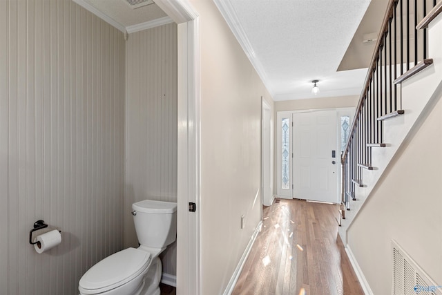 bathroom featuring ornamental molding, hardwood / wood-style floors, a textured ceiling, and toilet