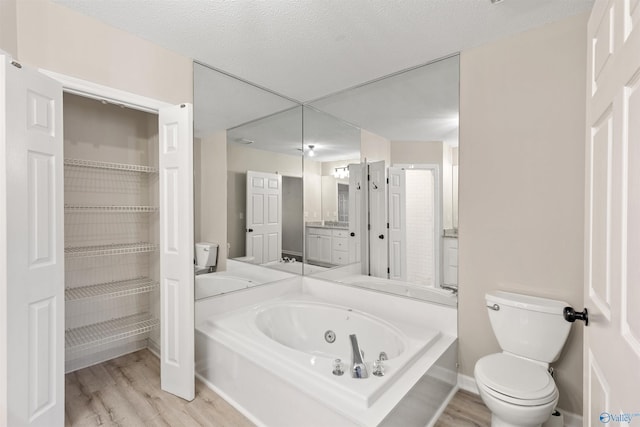 bathroom featuring hardwood / wood-style floors, toilet, vanity, a bathtub, and a textured ceiling