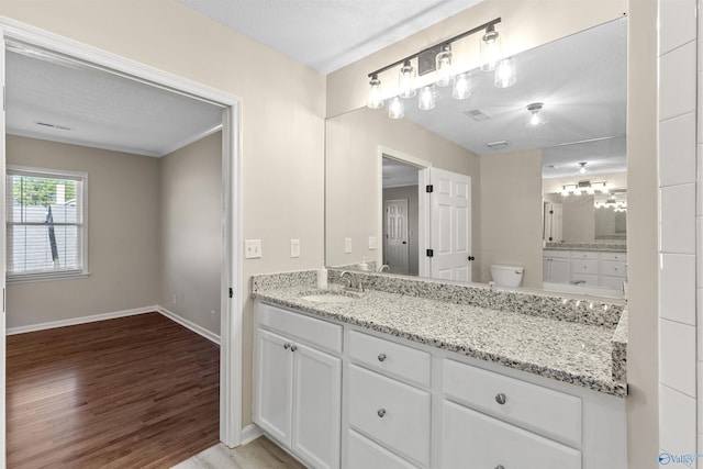 bathroom featuring toilet, a textured ceiling, hardwood / wood-style floors, ornamental molding, and vanity