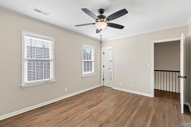 unfurnished room with ceiling fan, dark hardwood / wood-style flooring, ornamental molding, and a healthy amount of sunlight