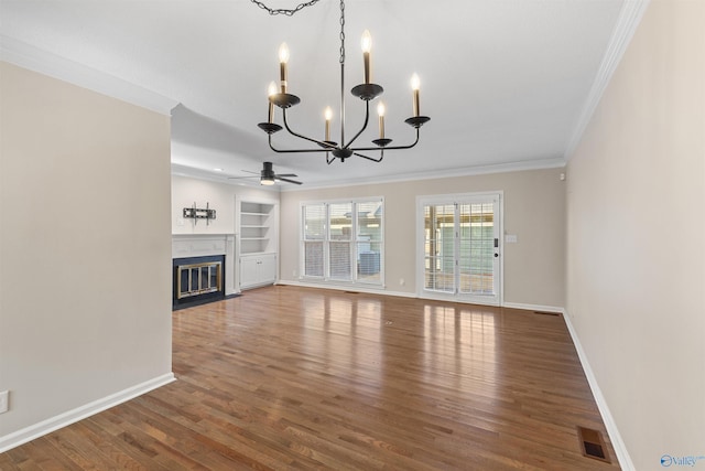 unfurnished living room with ceiling fan with notable chandelier, crown molding, built in features, and dark hardwood / wood-style floors