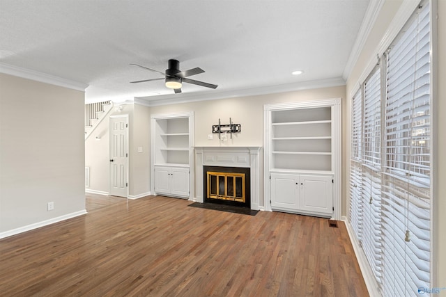 unfurnished living room featuring a textured ceiling, hardwood / wood-style floors, ceiling fan, built in features, and crown molding