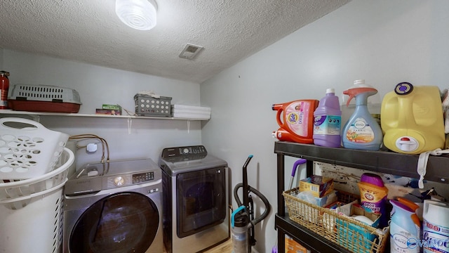 laundry area featuring a textured ceiling and washing machine and clothes dryer