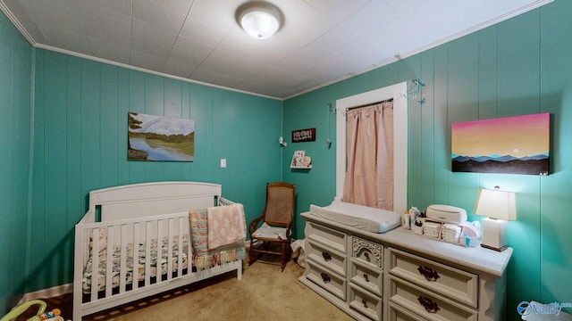 carpeted bedroom featuring a nursery area and crown molding