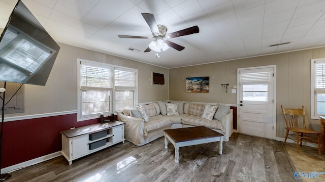 living room with ceiling fan, light hardwood / wood-style floors, wood walls, and ornamental molding