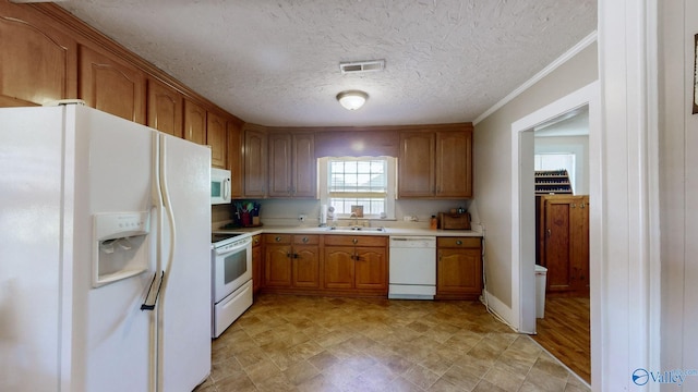 kitchen with a textured ceiling, crown molding, white appliances, and sink