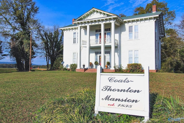 greek revival inspired property with a balcony and a front yard