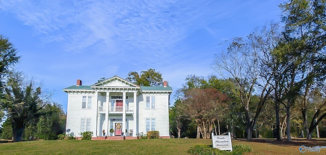 greek revival inspired property featuring a front lawn and a balcony