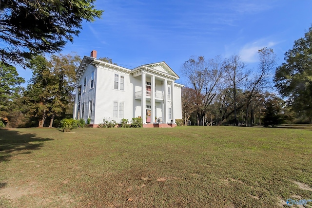 greek revival inspired property with a front lawn and a balcony