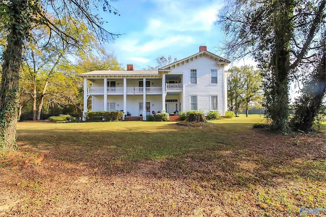 rear view of house featuring a balcony and a yard