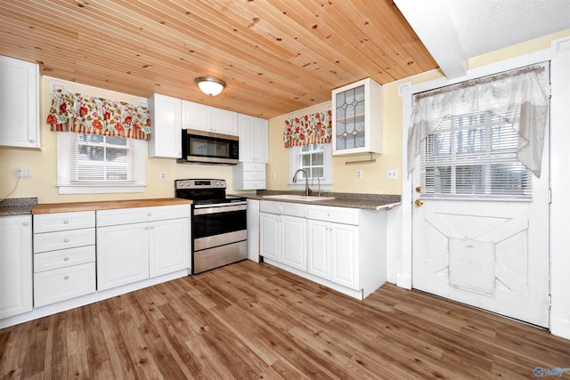 kitchen with light wood-type flooring, a sink, white cabinetry, appliances with stainless steel finishes, and glass insert cabinets